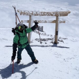 Um guia de montanhismo e snowboarding no Japão. Ele está usando roupas verde de inverno. Guia de montanhismo e snowboarding e esqui no Japão usando roupas verde de inverno, representando expedições guiadas de montanhismo, esqui e snowboard nas montanhas japonesas.