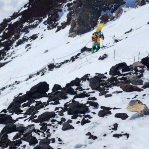 Um guia de montanhismo subindo uma montanha ingrime coberta por neve no Japão para praticar snowboarding. Guia de montanhismo subindo montanha íngreme com neve no Japão para snowboarding, representando guias especializados em snowboard de montanha e expedições de backcountry no Japão.